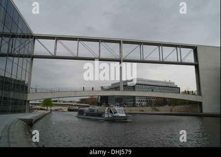 Cielo grigio vista chiatta turistici al di sotto di passerelle di collegamento di Paul Lobe Haus e Marie Elisabeth Luders Haus, il fiume Sprea, Berlino Foto Stock