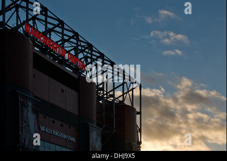 Un vicino della silhouette Alex Ferguson stand di Old Trafford, casa del Manchester United, tramonto sullo sfondo (solo uso editoriale). Foto Stock