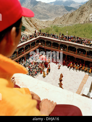 Giovane monaco sul tetto guardando la danza di maschere nel cortile durante il Gonpa Hemis Festival al convento Hemis, southeas Foto Stock