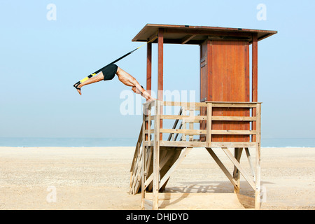 Uomo di sport sulla spiaggia con trx Foto Stock