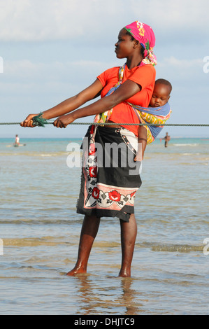 Gli abitanti di un villaggio tirando in reti da pesca. Isola di Benguerra, l'Arcipelago di Bazaruto. Mozambico. Africa orientale. Foto Stock