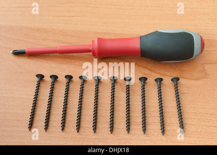 Cacciavite e viti sono su una tavola di legno Foto Stock