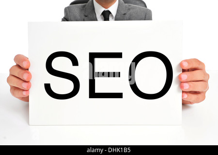 Un uomo che indossa una tuta tenendo un cartello con scritto la parola SEO, acronimo di ottimizzazione per i motori di ricerca, scritto in esso Foto Stock
