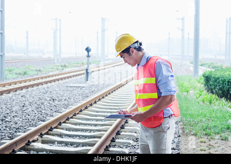 Ferrovia lavoratore nella protezione di usura di lavoro controllare i binari ferroviari Foto Stock