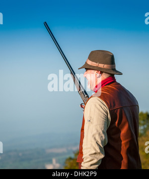 Un uomo con un colpo di pistola che indossa un cappello, sorgeva su un fagiano sparare in attesa per l'inizio della giornata di riprese Foto Stock