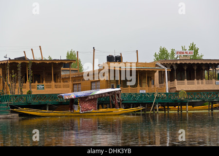 Shikara legata a houseboats in dal lago a Srinagar nel Kashmir, con 3 grandi case galleggianti sulla riva del lago. Foto Stock