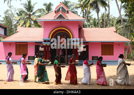 Un gruppo di donne con offerte e un sacerdote che circonda un tempio indù di Varkala, India, Foto Stock