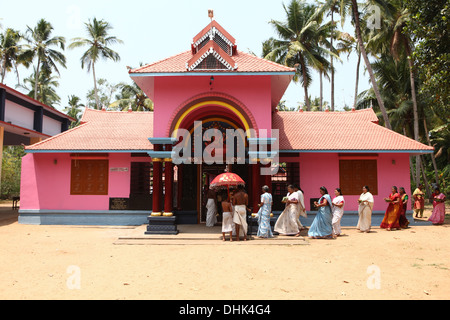 Un gruppo di donne con offerte e un sacerdote che circonda un tempio indù di Varkala, India, Foto Stock