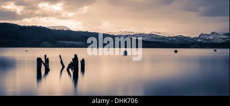 Una lunga esposizione immagine di un vecchio collassato jetty di Windermere guardando verso il Langdales nevoso Foto Stock