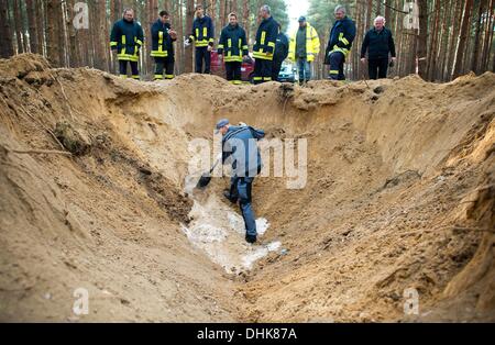Fuerstenwalde, Germania. Xii Nov, 2013. Matthias Metke della bomba team di smaltimento della polizia sorge in un cratere in un bosco vicino a Fuerstenwalde, Germania, 12 novembre 2013. Un 100 kilo russo bomba aerea dalla Seconda Guerra Mondiale è stata soffiata fino vicino all'Autostrada 12 in Fuerstenwalde. Foto: PATRICK PLEUL/dpa/Alamy Live News Foto Stock