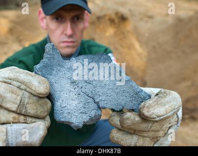 Fuerstenwalde, Germania. Xii Nov, 2013. Matthias Metke della bomba team di smaltimento della polizia detiene un frammento di bomba in un cratere in un bosco vicino a Fuerstenwalde, Germania, 12 novembre 2013. Un 100 kilo russo bomba aerea dalla Seconda Guerra Mondiale è stata soffiata fino vicino all'Autostrada 12 in Fuerstenwalde. Foto: PATRICK PLEUL/dpa/Alamy Live News Foto Stock