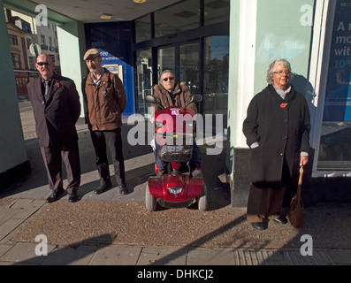 Godersi il sole invernale, curiosi guarda una parata militare in Brighton Foto Stock