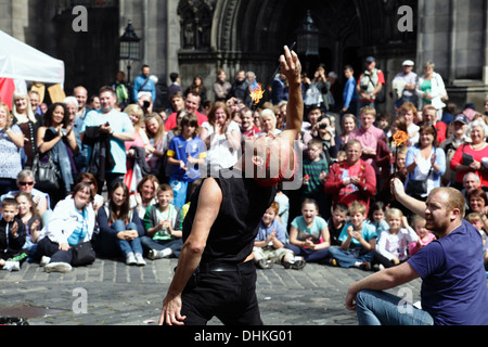 L'artista di strada Mighty Gareth mangia il fuoco con l'aiuto di un volontario durante l'Edinburgh International Festival Fringe, Scozia, Regno Unito Foto Stock