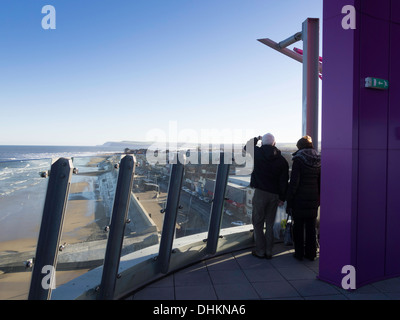 Un giovane godendo il sole di autunno guardando ad est verso Saltburn sulla piattaforma di osservazione del faro redcar cleveland, Regno Unito Foto Stock