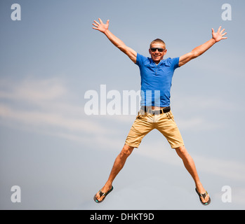 Uomo felice jumping, cielo blu su sfondo Foto Stock