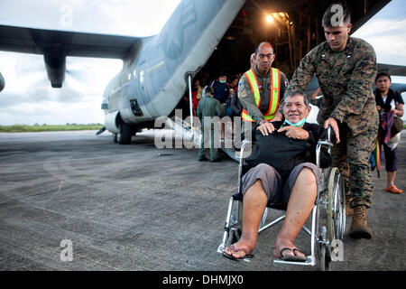 Marines americani aiuto offload civili filippini al di fuori di un'U.S. Marine C-130 Hercules aeromobili a Villamor Air Base evacuati da Tacloban Novembre 12, 2013 a Manila nelle Filippine. Il super typhoon hanno devastato ampie zone delle isole e ucciso come molti come 10.000 persone. Foto Stock