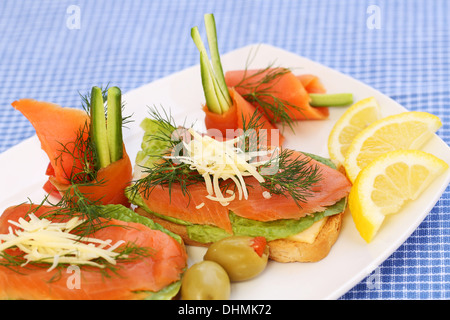 Panini con salmone, formaggio, lattuga, erbe su piastra, olive e limoni. Foto Stock