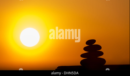 Silhouette di una piramide di pietre su uno sfondo di un tramonto Foto Stock