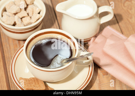 Tazza di caffè, zucchero, panna sul tavolo per la colazione Foto Stock