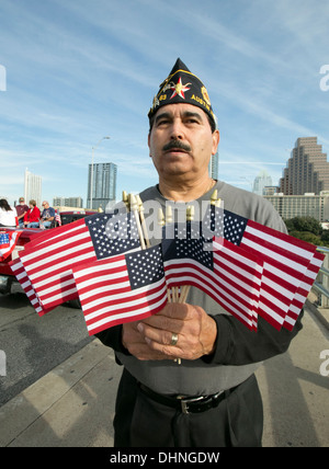 Maschio militare ispanico veterano contiene numerose piccole bandierine americane durante un veterano del giorno parade di Austin in Texas Foto Stock