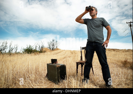 L'uomo con un binocolo in un campo Foto Stock