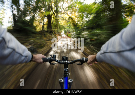 Vista sopra le barre del manubrio lungo viale alberato fangoso percorso nuziale paese lane rive scoscese andando veloce verso il sole Foto Stock