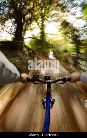 Vista sopra le barre del manubrio lungo viale alberato fangoso percorso nuziale paese lane rive scoscese andando veloce verso il sole Foto Stock