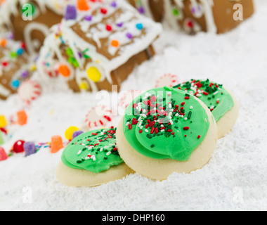 Close up foto di zucchero glassato biscotti di Natale con Gingerbread case circondate da neve alimentato in background Foto Stock