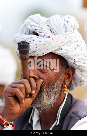 Uomo indiano fumatori Chillum artigianali tubazione in Pushkar camel Fair, India. Foto Stock