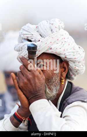Uomo indiano fumatori Chillum artigianali tubazione in Pushkar camel Fair, India. Foto Stock