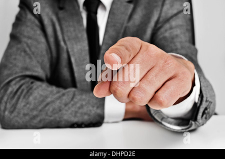 L uomo indossa una tuta seduti a un tavolo puntando il dito per l'osservatore Foto Stock