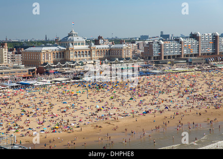 Paesi Bassi, Scheveningen, affollata spiaggia, le persone a prendere il sole godendo di acqua di mare. Backgr Grand Hotel Amrâth Kurhaus. Antenna Foto Stock