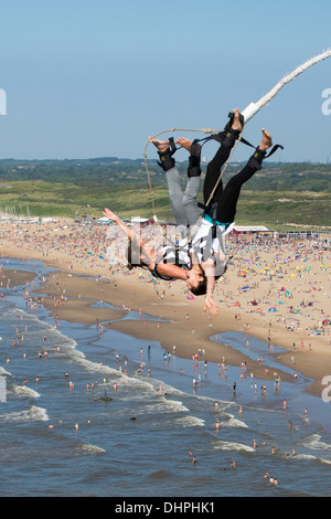 Paesi Bassi, Scheveningen, nei pressi dell'Aia. Bungee Jumping dal molo. Spiaggia affollata in background. Foto Stock