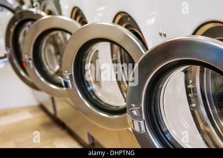 Una fila di macchine lavatrici industriali in una lavanderia pubblica Foto Stock