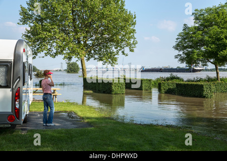 Paesi Bassi, Slijk-Ewijk, Caravan in campeggio nelle pianure alluvionali del fiume Waal. Donna che guarda all'acqua alta. Foto Stock