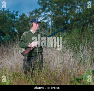 Un uomo con un fucile da caccia si fermò in attesa per l'inizio di un fagiano sparare in Inghilterra Foto Stock