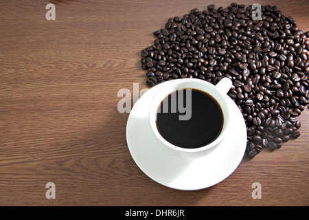 La messa a fuoco delle immagini tazza di caffè e i chicchi di caffè sul tavolo il legno vecchio. Foto Stock