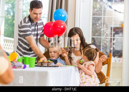 Famiglia mangiare tortine alla festa di compleanno Foto Stock