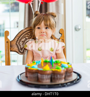 Compleanno ragazza seduta davanti a torta Foto Stock