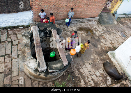 Le donne indiane, uomini e bambini il prelievo di acqua da un pozzo in una zona rurale villaggio indiano street. Andhra Pradesh, India Foto Stock