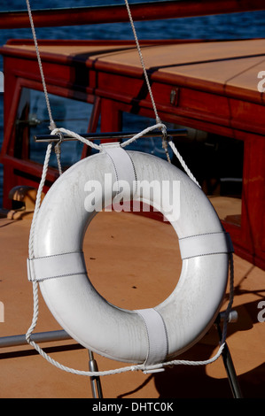 Anello White LIFE su barca a vela vintage in legno. Questo dispositivo è fatto di materiale galleggiante per tenere qualcuno a galla in acqua. Foto Stock