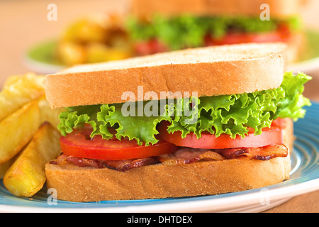 Freschi Fatti in casa BLT (pancetta lattuga e pomodoro) panino con patatine fritte sulla piastra blu Foto Stock