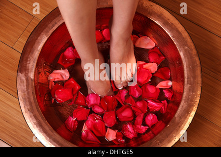 Donna di piedi nel bacino del riempimento con acqua e foglie di rose Foto Stock