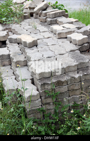 I mattoni usati nella costruzione collocata sull'erba a fianco del marciapiede. Foto Stock