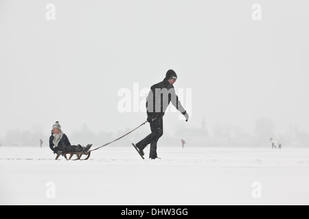 Paesi Bassi, Loosdrecht, laghi chiamato Loosdrechtse Plassen. L'inverno. Padre pattinaggio su ghiaccio con il figlio sulla slitta Foto Stock