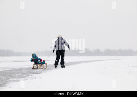 Paesi Bassi, Loosdrecht, laghi chiamato Loosdrechtse Plassen. L'inverno. Madre pattinaggio sul ghiaccio con bambino sulla slitta Foto Stock