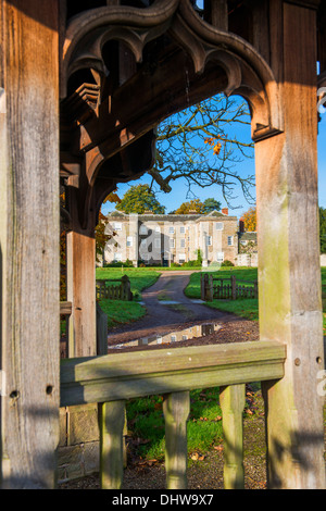 Autunno sole su cinquecento Morville Hall, incorniciato da lych gate del la chiesa di Saint Gregory, vicino Bridgnorth, Shropshire. Foto Stock