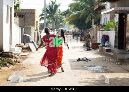 Le donne indiane che porta un vaso in materia plastica con acqua da un tubo montante in un territorio rurale villaggio indiano street. Andhra Pradesh, India Foto Stock