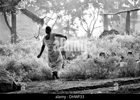 Donna indiana che porta un vaso in materia plastica con acqua proveniente da una pompa a mano in un territorio rurale villaggio indiano. Andhra Pradesh, India. In bianco e nero. Foto Stock