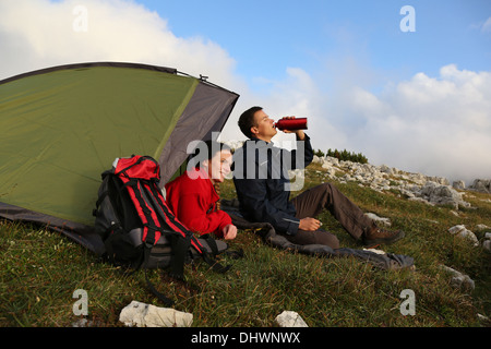 Giovani camping in montagna di sera Foto Stock